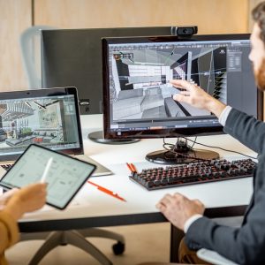 Two creative office employees making interior design on the computer and digital tablet at the modern office of architectural firm. Concept of 3d modeling and digital Interior designing